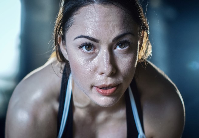 Frau fasst sich an den Bauch Elektrolyte bei körperlicher Anstrengung